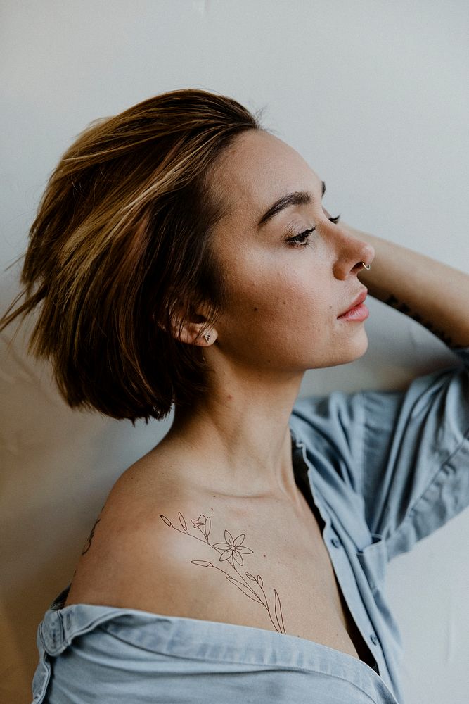 Portrait of a short haired woman with a floral tattoo on her shoulder 