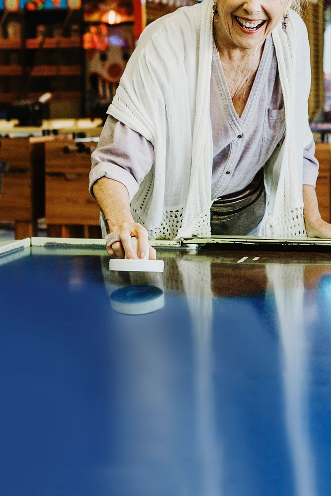 Senior woman playing air hockey