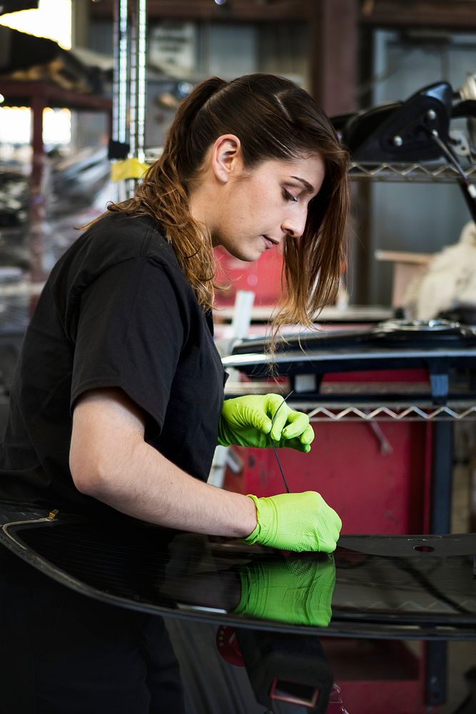 Female mechanic pulling out the weather seal of a vehicle