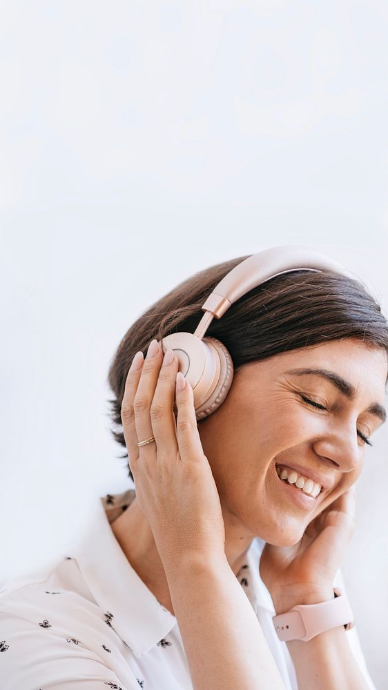 Happy woman with headphones on the couch mobile phone wallpaper