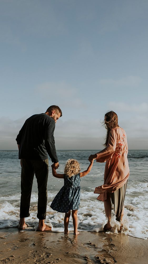 Parents holding daughter's hand at the beach design space