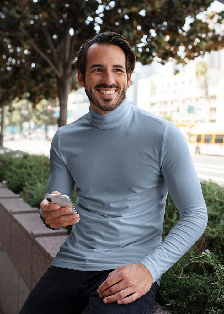 Businessman in blue turtleneck sitting and smiling in the city