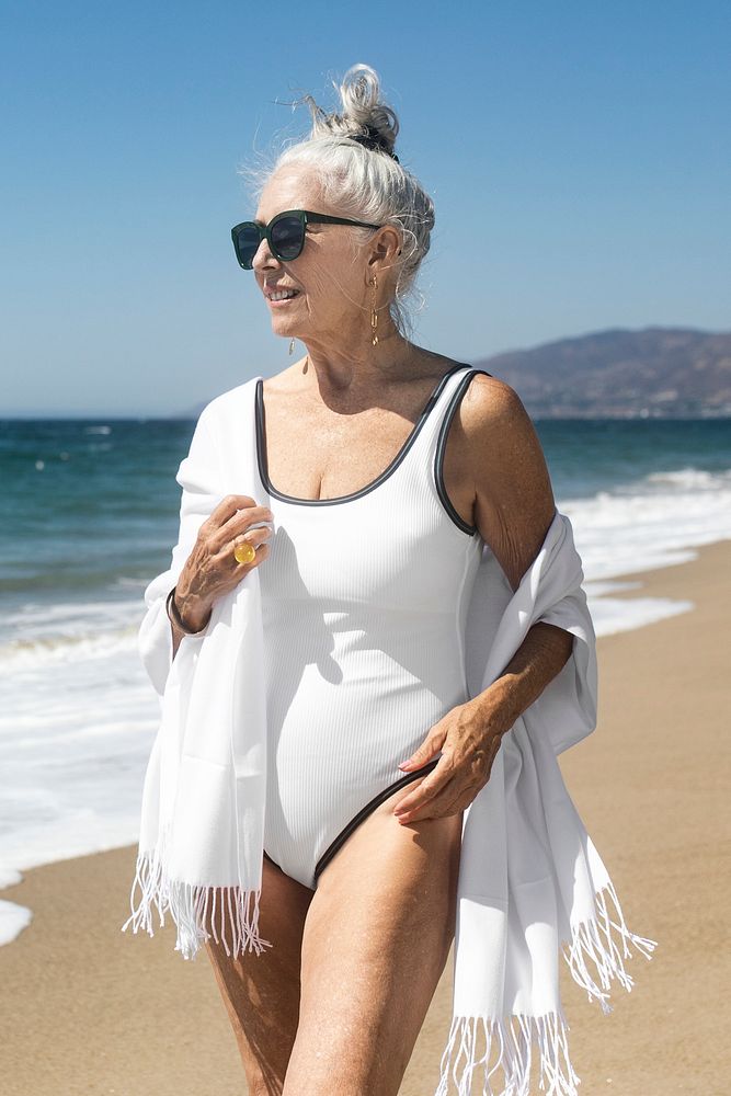 Senior woman in swimsuit and scarf chilling at the beach portrait