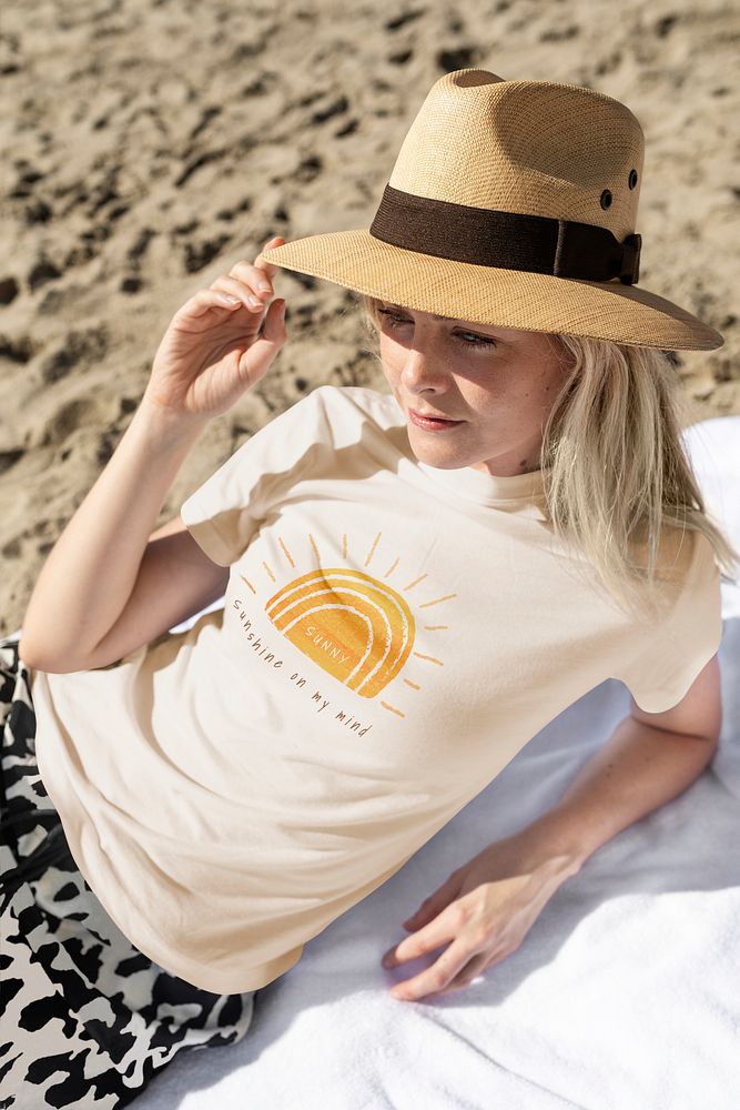 Woman in panama hat wearing cream screened tee chilling at the beach