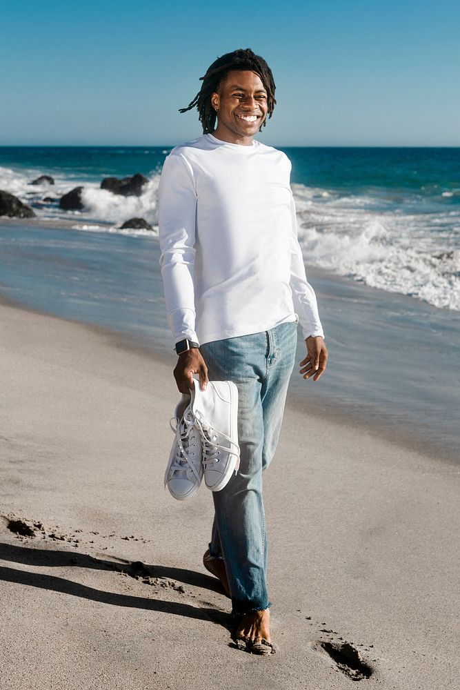 Man in white long sleeve tee walking on the beach