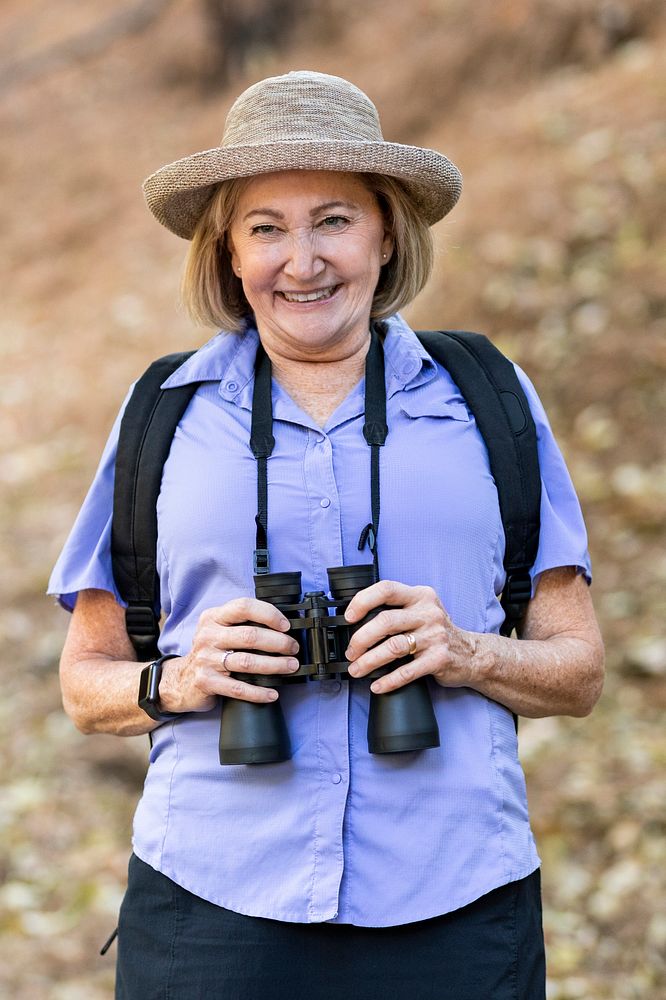 Senior woman with binoculars in the forest 