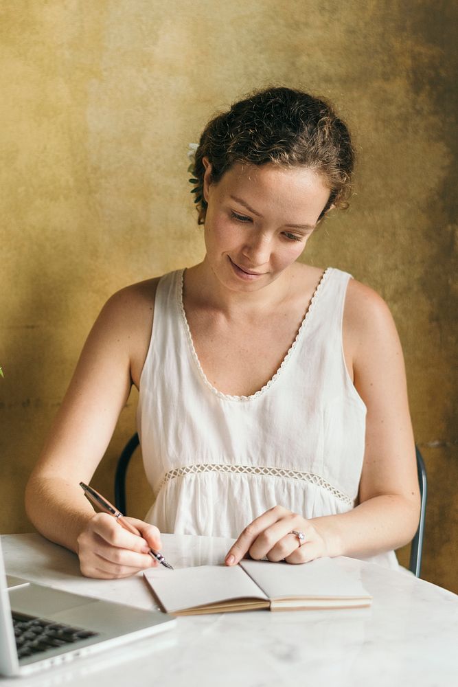 Beautiful female journalist writing her note at a cafe