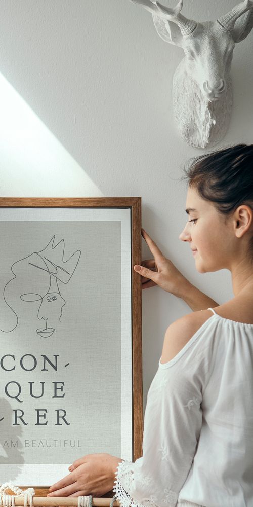 Girl decorating a wall with a conqueror frame