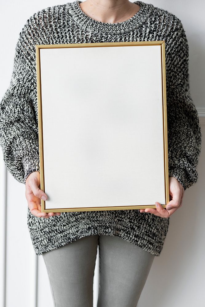 Woman in a black sweater holding a wooden frame