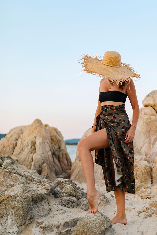 Woman wearing a straw hat walking alone the beach