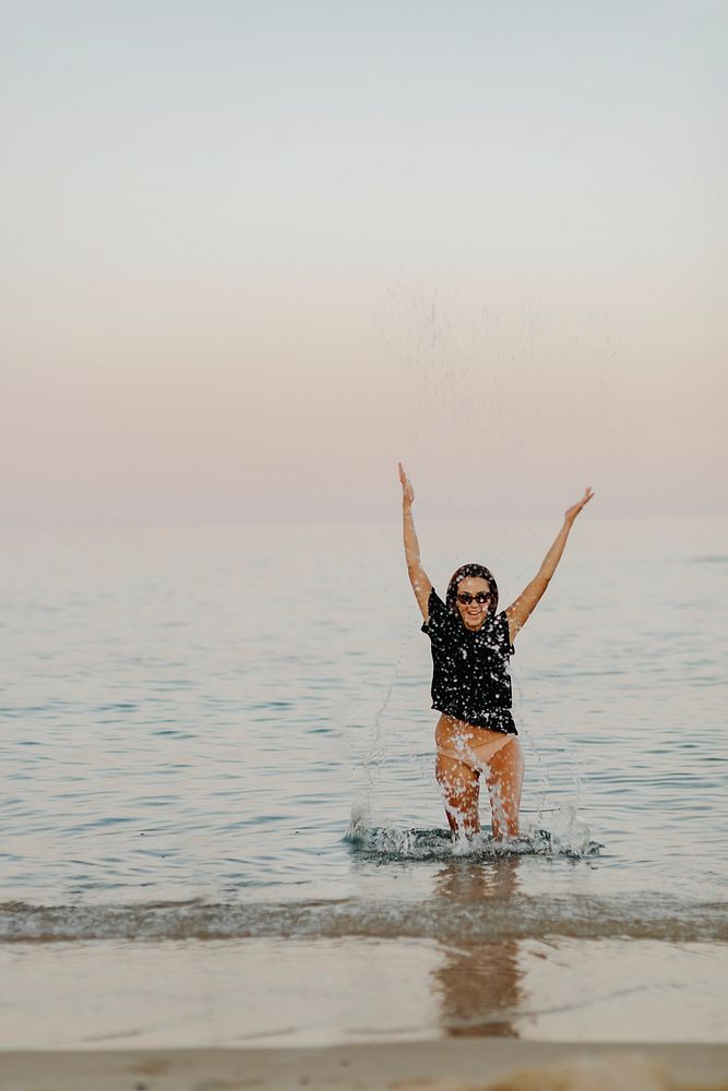 Cheerful girl splashing water at the beach
