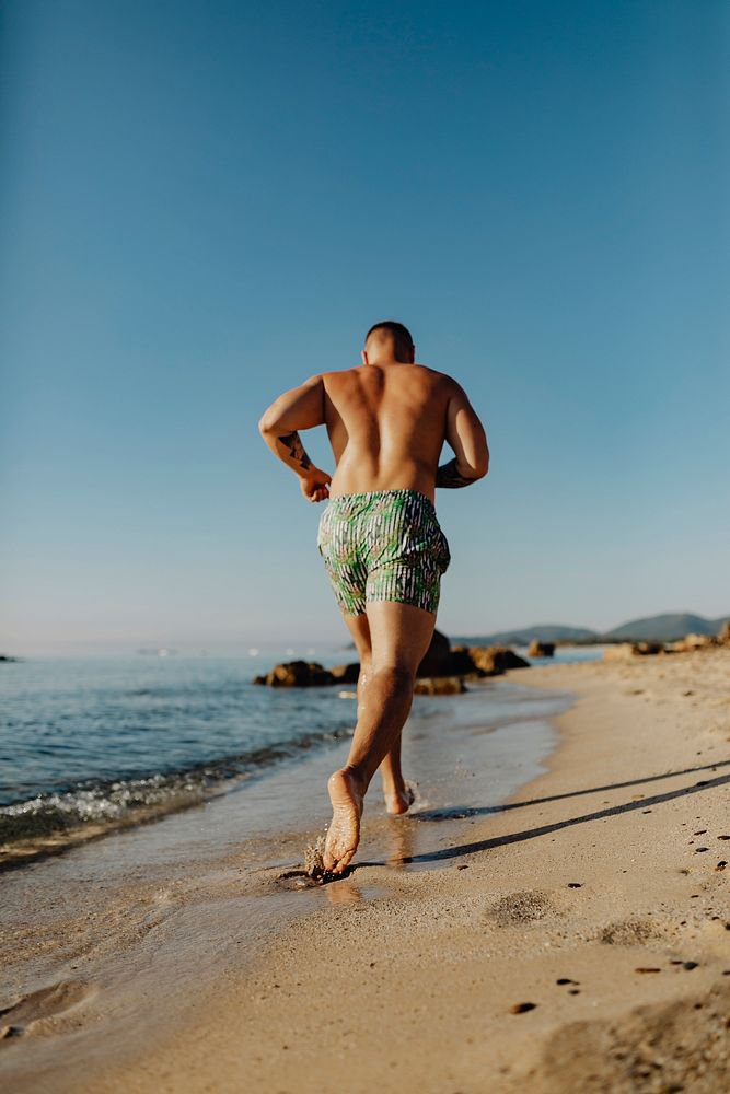Rearview of man jogging along the beach