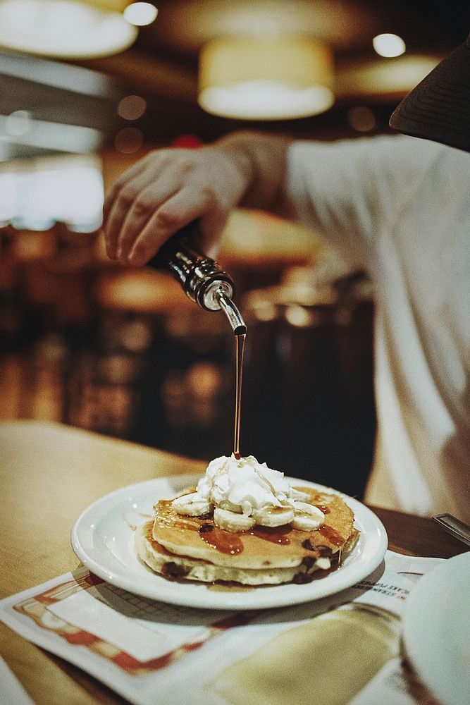 Man pouring maple syrup onto fluffy pancakes