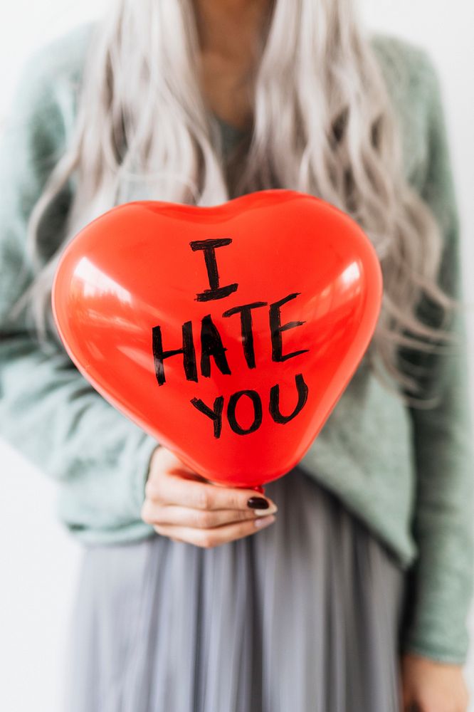 Woman showing a heart red balloon with I hate you on it