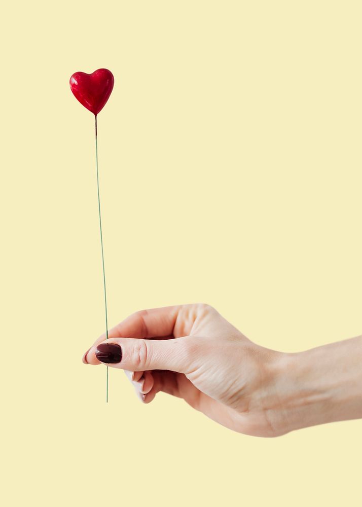 Woman holding a red heart on a stick psd