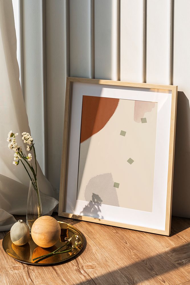 Picture frame mockup by a white wall on the wooden floor