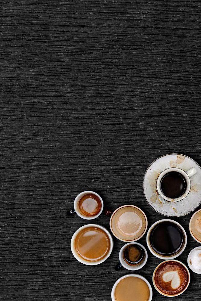 Assorted coffee cups on a black wooden plank textured background