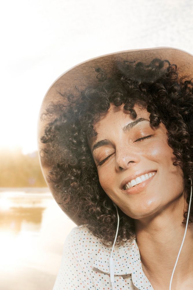 Woman with curly hair wearing earphones with nature view remixed media