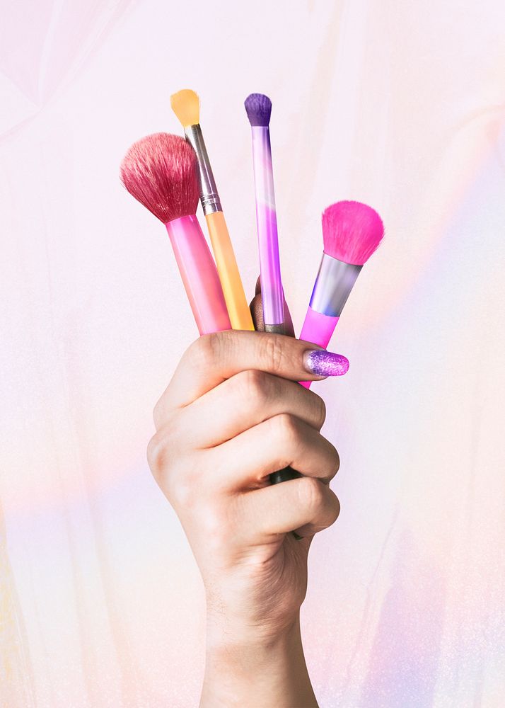 Hand holding makeup brushes, cosmetics design