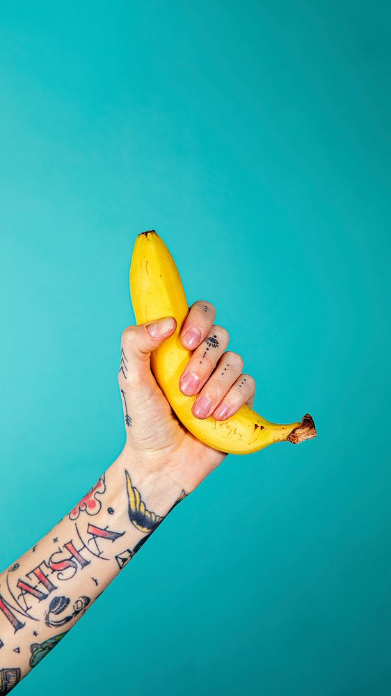 Tattooed hand with a ripe banana mobile phone wallpaper