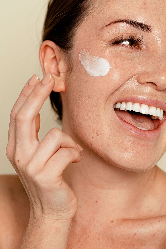 Happy woman applying facial skincare