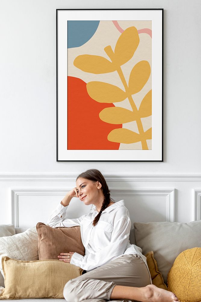 Woman relaxing in living room, botanical framed picture on a wall