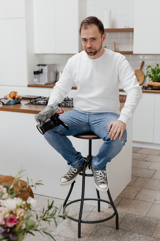 Happy man sitting on a stool with a camera