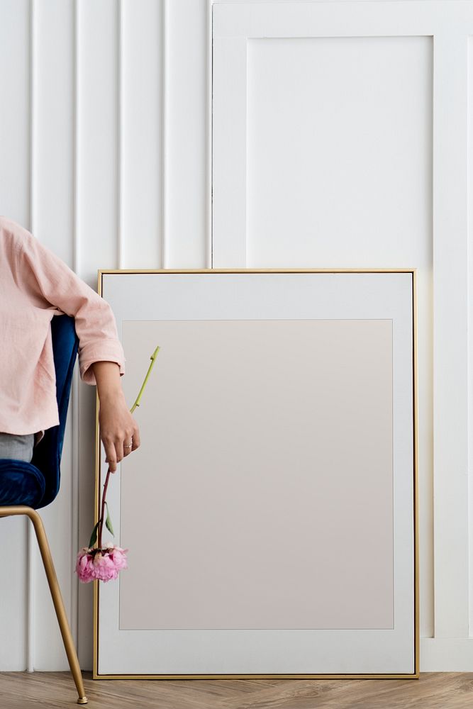 Woman holding a flower sitting by a frame mockup