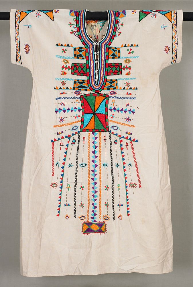 elaborately embroidered dress with a variety of stitches used to create a wide front panel of geometric designs; colors…
