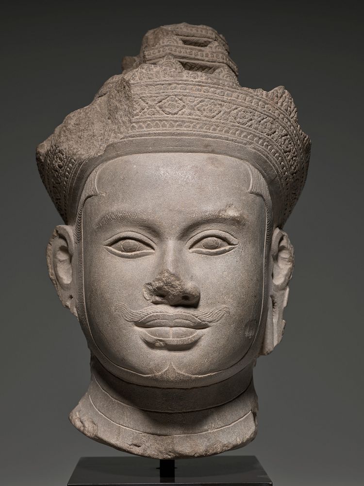 Head from an image of a diefied king carved in sandstone wearing a very elaborate crown and a diadem tied with a knot at the…