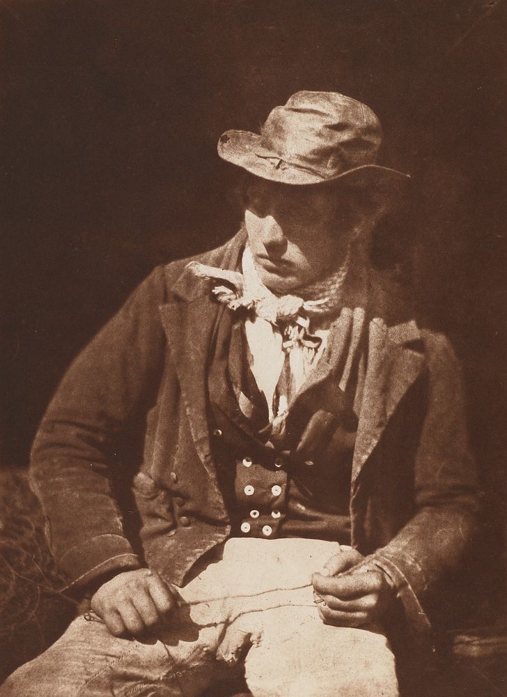 seated man wearing a hat, short jacket, vest, and bandana, looking down toward lower left corner; sepia toned. Original from…