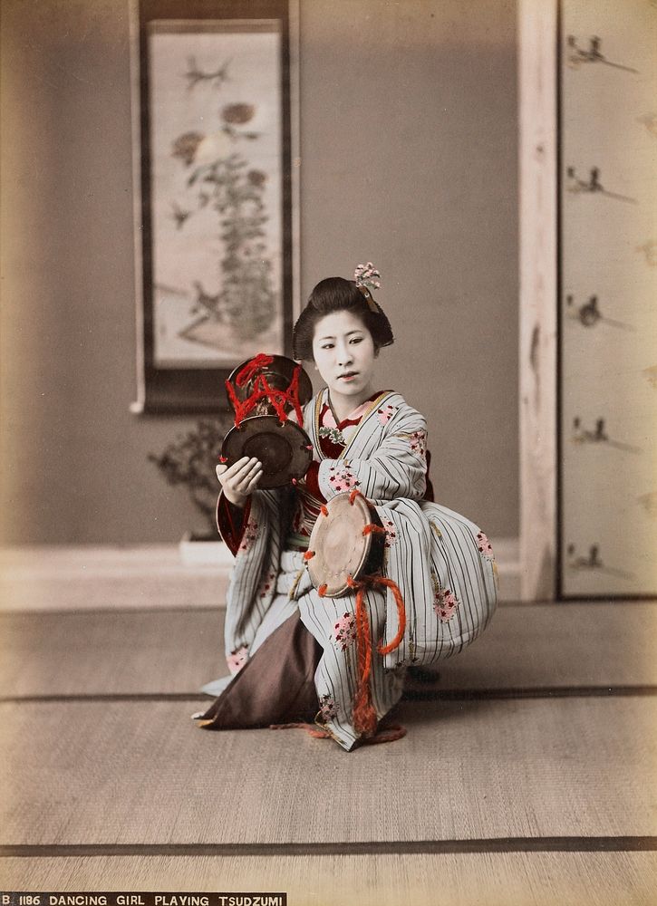 Crouching girl wearing blue striped kimono with pink and red flowers, playing two drums. Original from the Minneapolis…