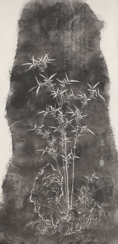 Black and white rubbing: large, dark, stone like figure with inscription at URQ in background; bamboo shoots at center;…