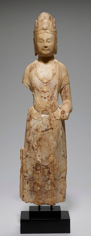 Standing Bodhisattva of white marble, right arm broken off below shoulder, left above wrist. Figure wears narrow scarf tied…