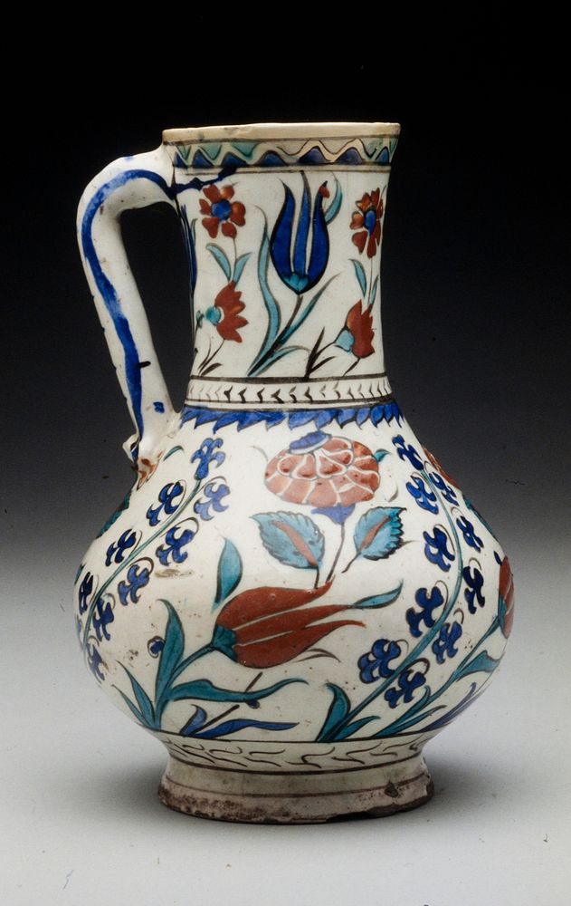Pitcher; with straight handle; white glaze with floral design in dark blue turquoise blue and tomato red with watery black…