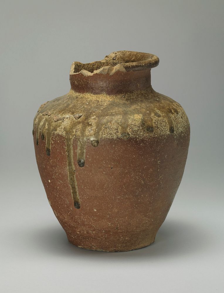 jar with narrow base, wider shoulder; short neck with rolled lip; much of neck and lip are missing; dark brown glaze with…
