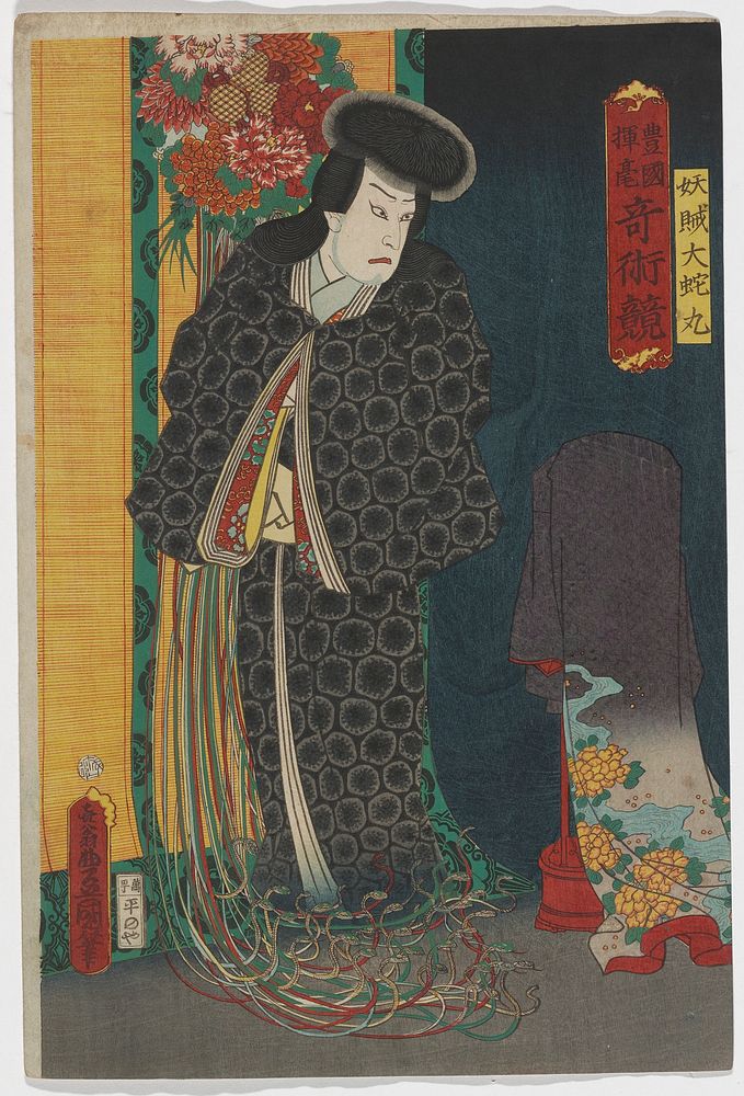 Standing figure wearing a black kimono with round patterning; floral wall hanging behind figure's head with long ribbons…