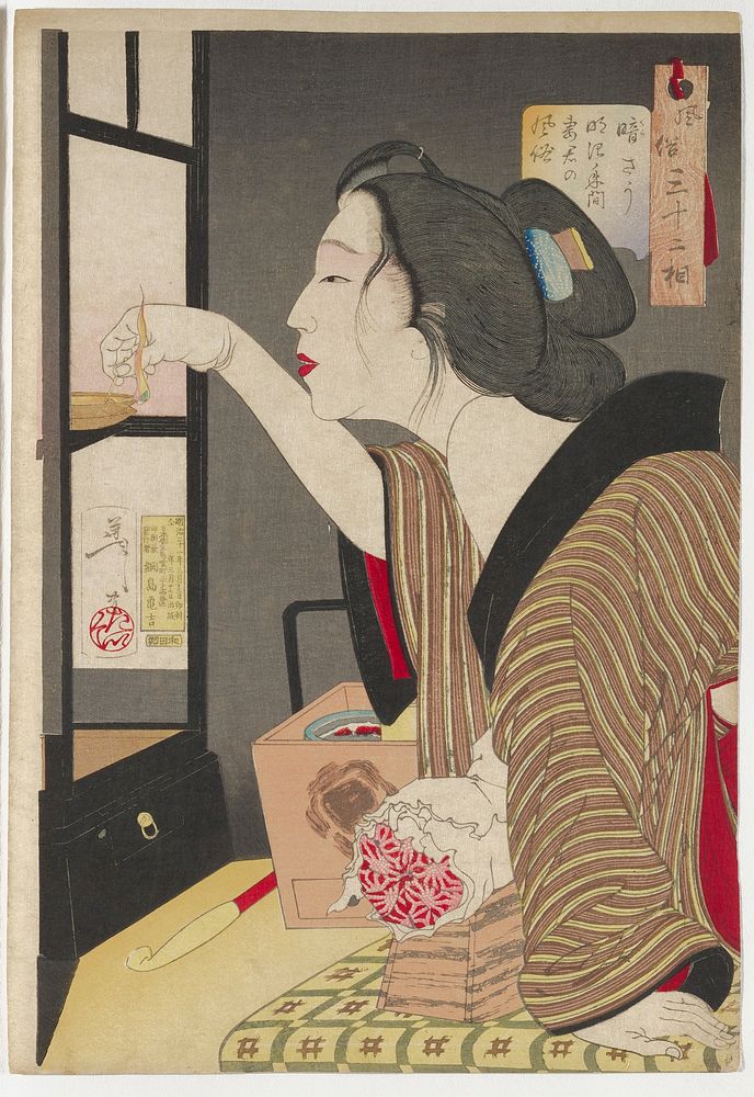 woman leaning forward, with her brown and yellow striped kimono with black collar slipping off her PL shoulder, lighting a…