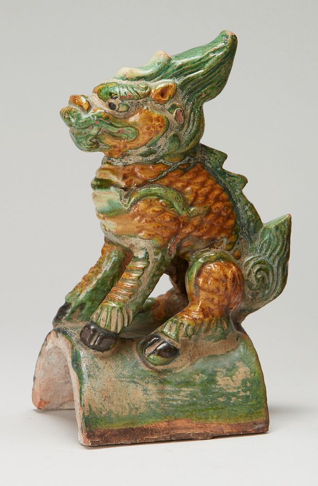 seated beast on an arched tile; green and ochre glaze with black hooves, painted hair and tail; not identical pair. Original…