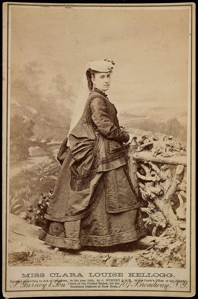 American actress; full-length portrait of a woman in profile from PR side with head turned to PR leaning against rustic…