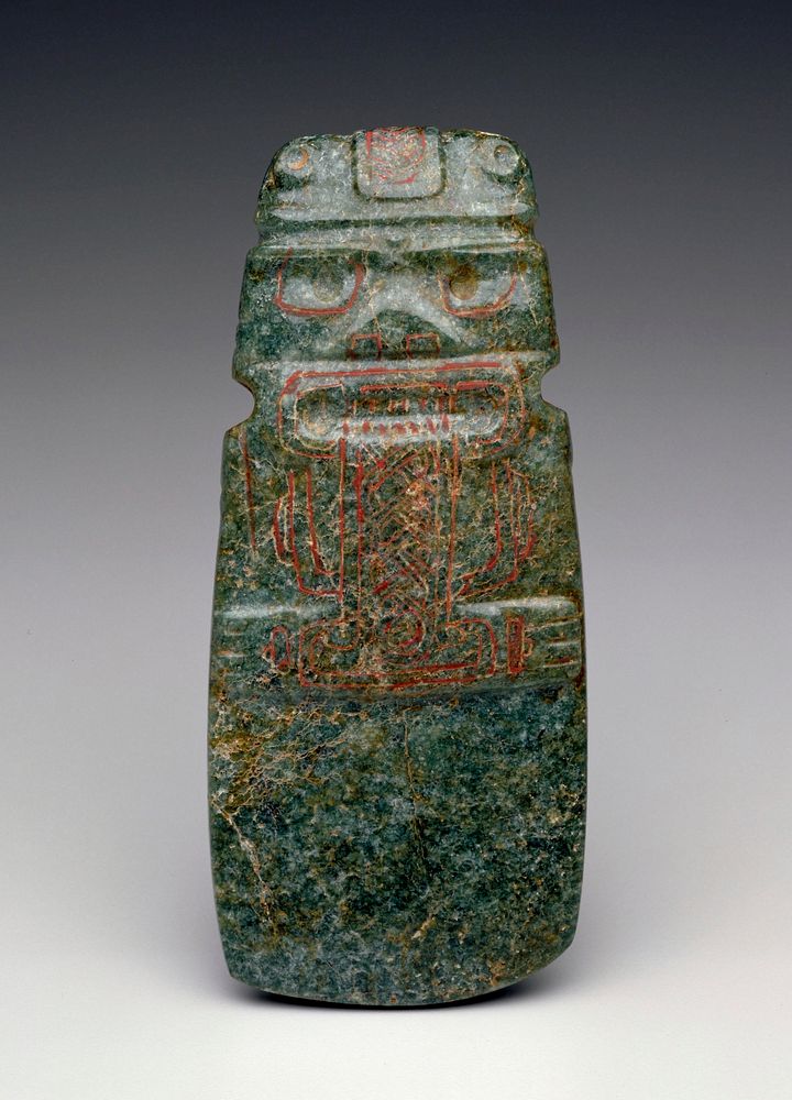 green, tan and white mottled stone; top carved with squat figure with long plaited beard; red pigment in crevices of…