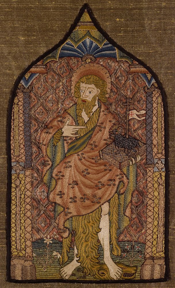 Embroidered panel in the shape of a cathedral window with black border; St. John standing with book in proper left hand;…