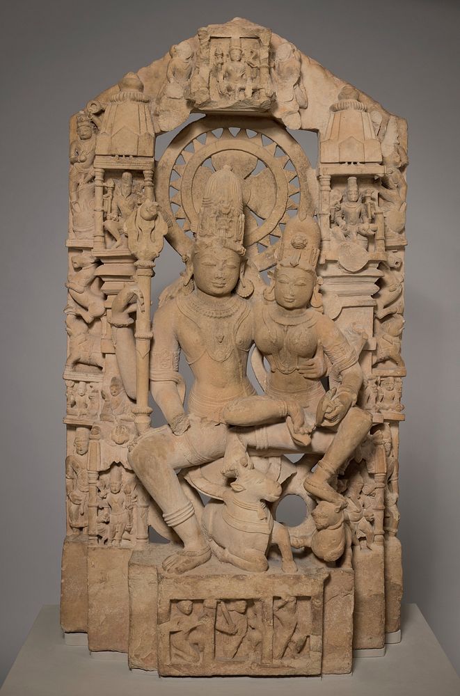 husband and wife seated on a lotus in the pose of royal ease and intimacy with bull and tiger underfoot; symmetrical…