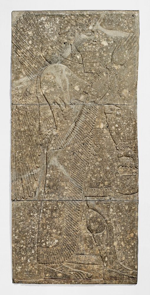 low relief carving of a Winged Genius, from the Northwest palace of Ashur-Nasir-Pal at Nimrud; a wide band of inscribed…