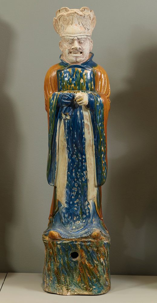 Dignitary, probably a civil counsellor. Glazed pottery tomb figure, one of a pair, mounted on a stand. The costume is…