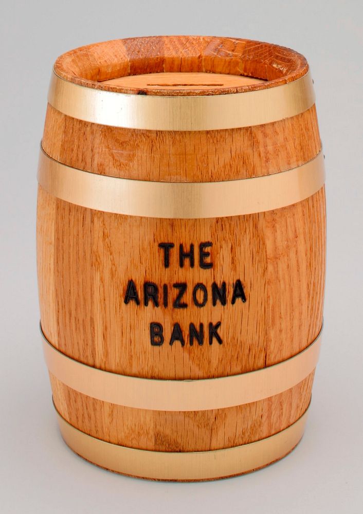 bank shaped as a barrel with brass bands; slit on top; "THE ARIZONA BANK" printed on front; plastic combination key on…