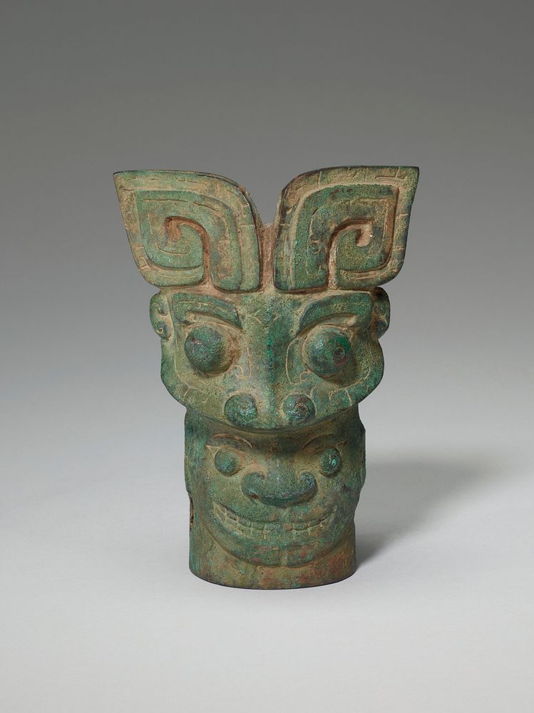 An eccentric combination of four masks occurs on this bronze. A forceful t'ao-t'ieh head with recumbent C-shaped horns, the…