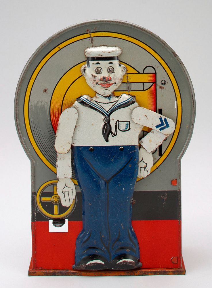 tin bank with standing sailor on front; sailor is wearing blue and white uniform with black shoes; lever on front causes…