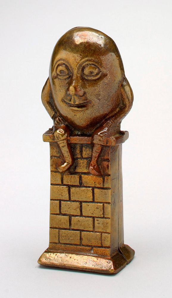 brass egg with face, arms and legs, Humpty Dumpty smiling and sitting on a brick wall; made in 2 parts- front and back.…