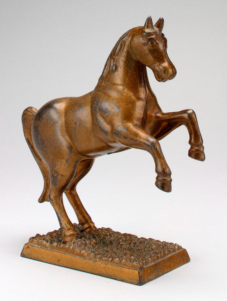 bronze color horse with two front legs off ground; coin slot back of neck; standing on an attached rectangular base.…